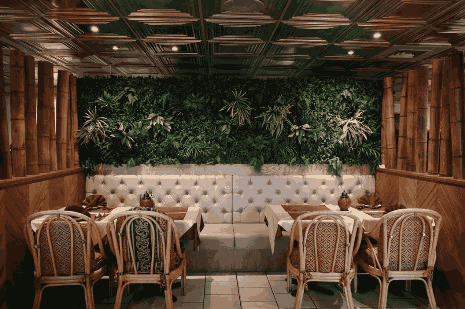Contemporary outdoor living space with a vertical garden, wooden deck, decorative lighting, and sustainable landscape design by Spaces & Places in Lahore.